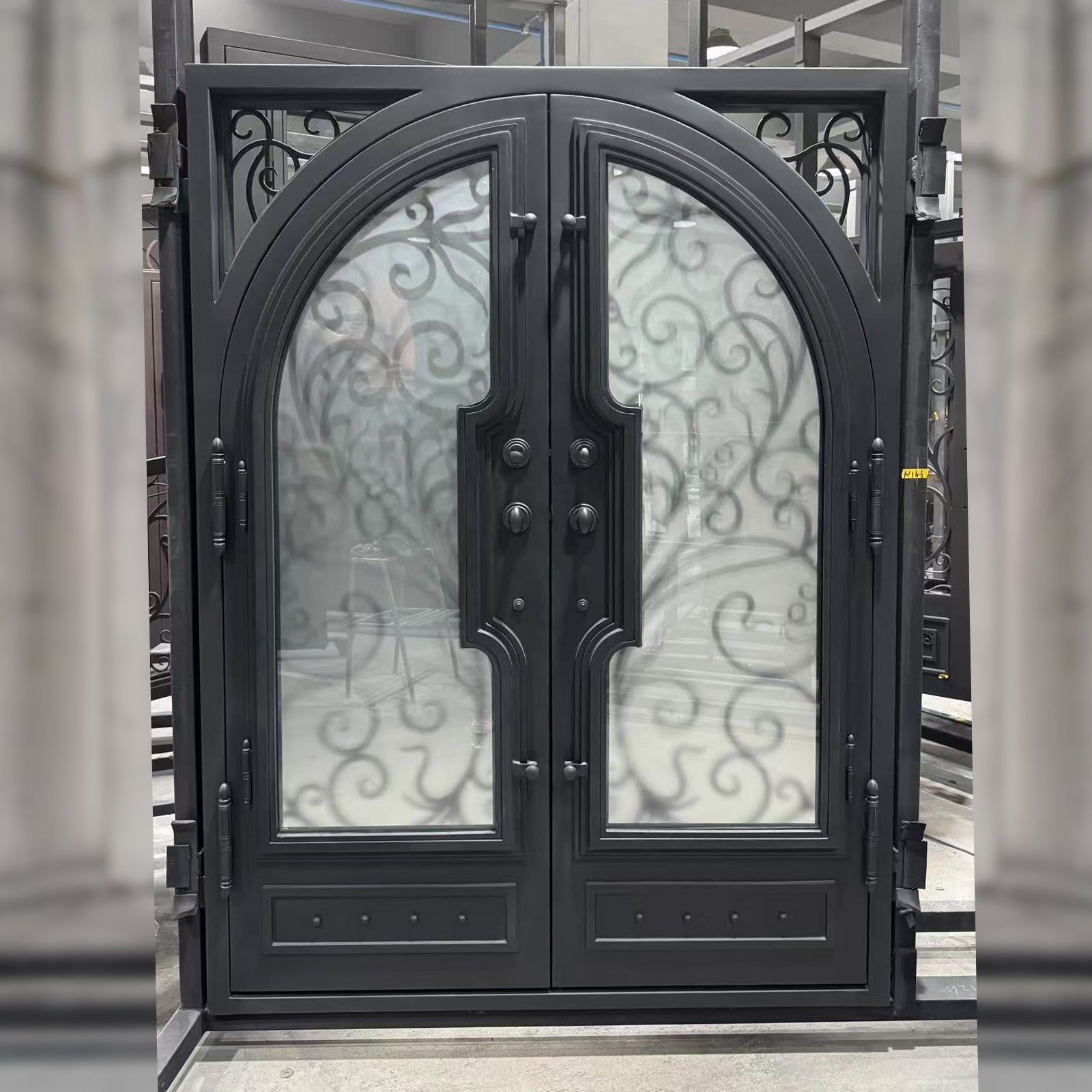 Decorative black metal double doors with glass panels in a showroom setting.