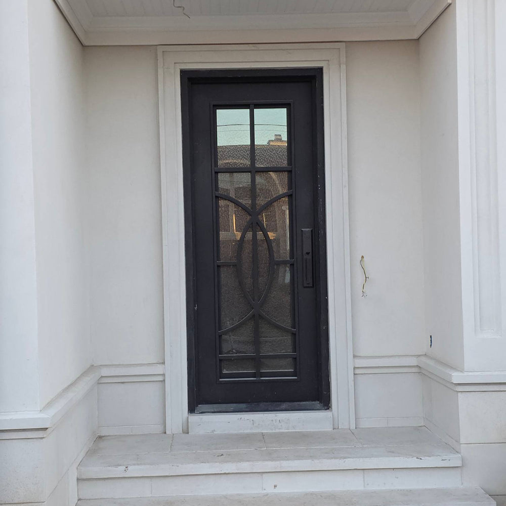 Black iron front door with decorative glass panel on a white house