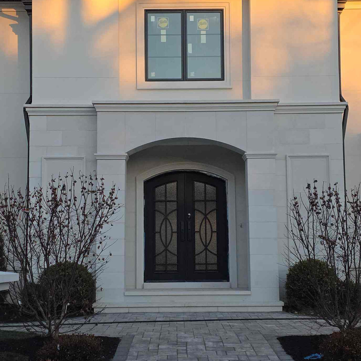 Elegant house exterior with a black iron door and decorative elements.