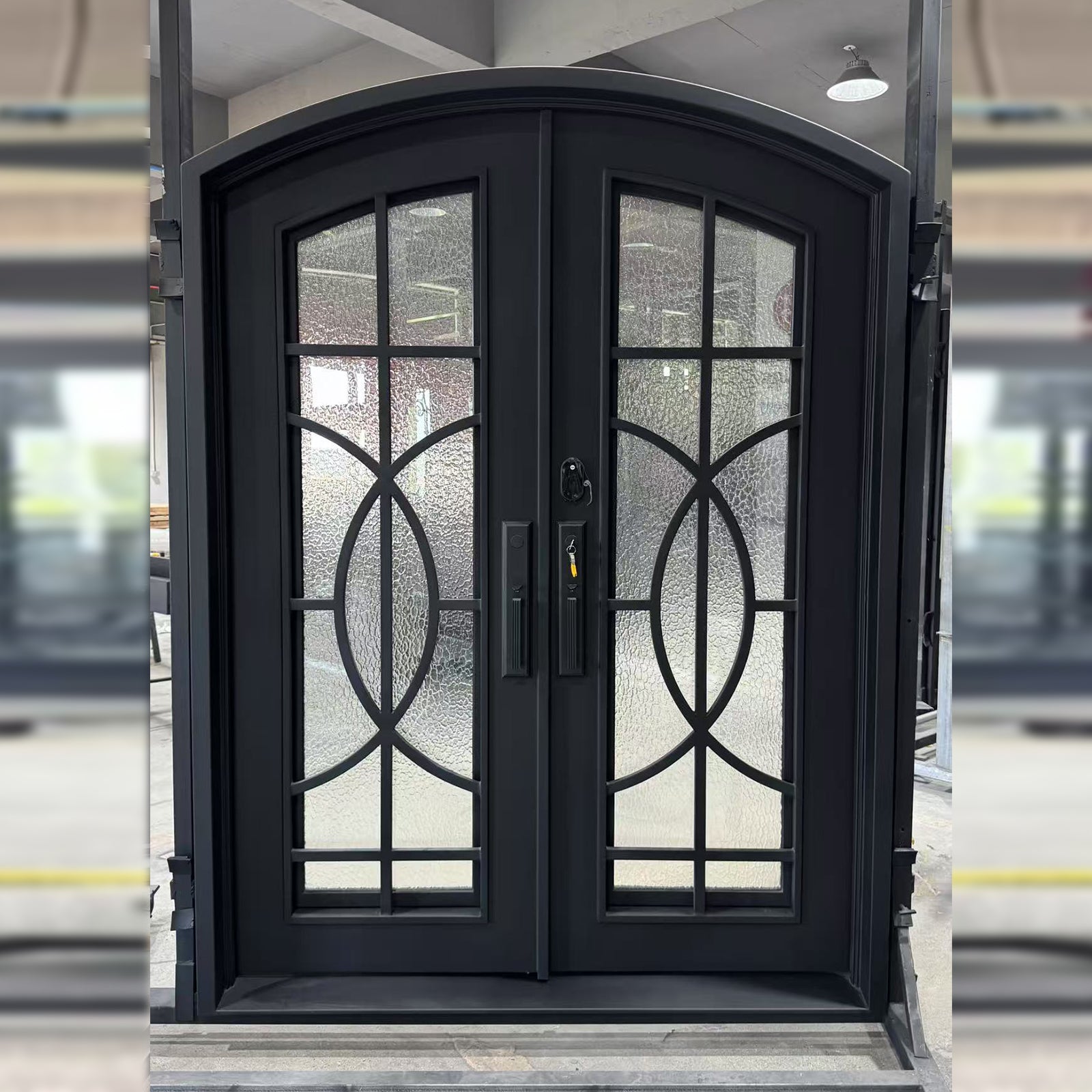 Black wrought iron door with decorative glass panels in a showroom setting